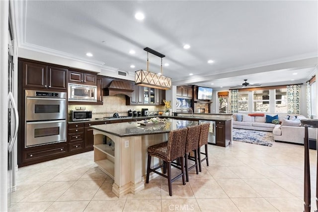 kitchen with a peninsula, premium range hood, stainless steel appliances, and dark brown cabinets