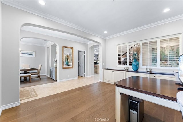 kitchen featuring light wood-style floors, arched walkways, white cabinets, and ornamental molding