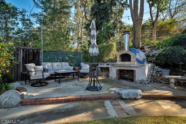 view of patio / terrace featuring an outdoor living space with a fireplace and fence