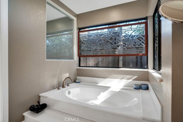 full bath featuring a textured wall and a garden tub