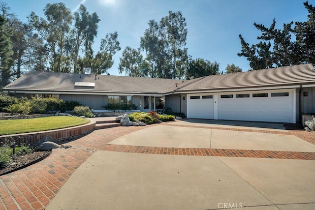 single story home featuring a garage, concrete driveway, a front yard, and a tile roof