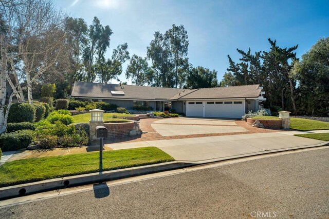 ranch-style home featuring driveway, an attached garage, a front yard, and a tiled roof