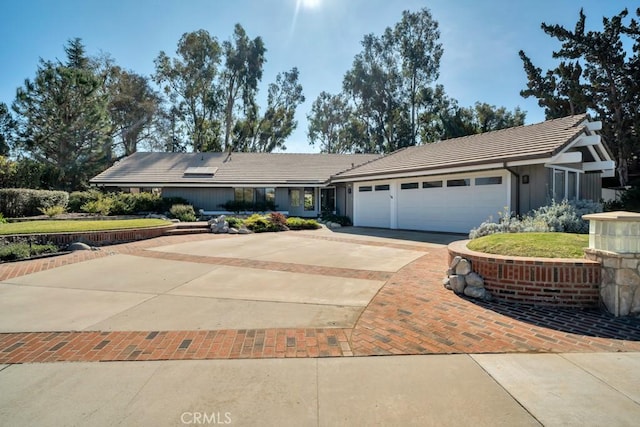 ranch-style home featuring concrete driveway, a tiled roof, and an attached garage