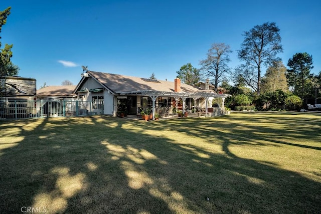 back of house featuring a chimney, fence, a pergola, and a yard