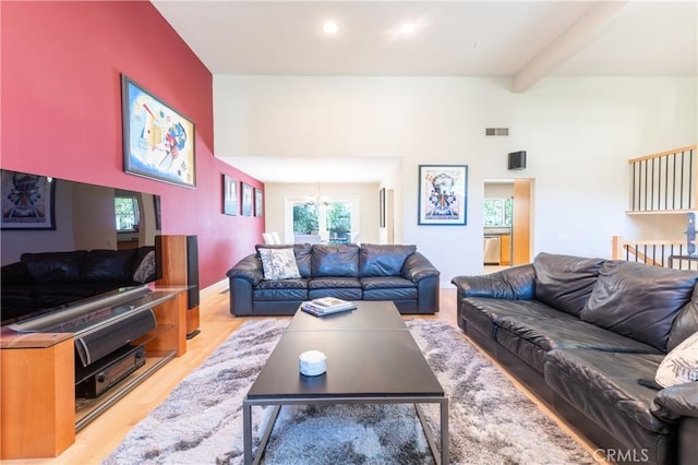 living room with a towering ceiling, light wood-style floors, visible vents, and beam ceiling