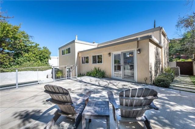 rear view of house featuring fence, a patio, and stucco siding