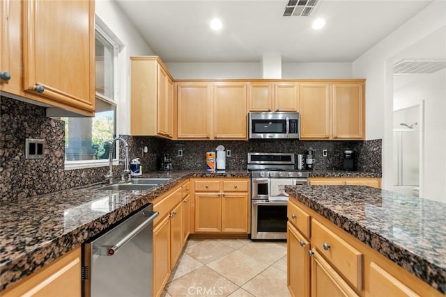 kitchen featuring visible vents, appliances with stainless steel finishes, a sink, and light brown cabinetry