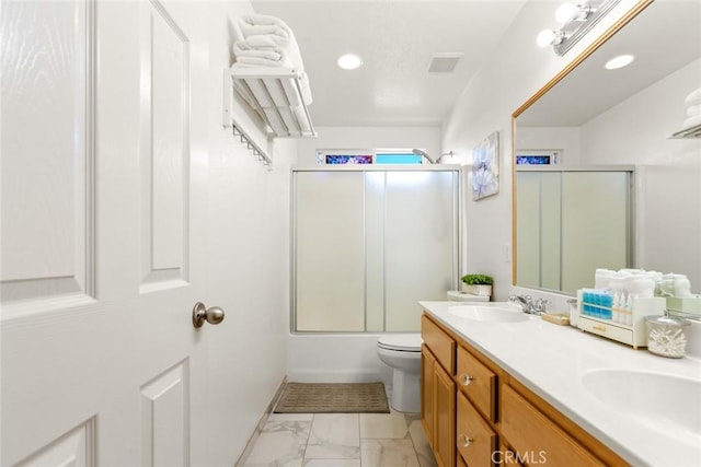 full bathroom featuring marble finish floor, bath / shower combo with glass door, double vanity, toilet, and a sink