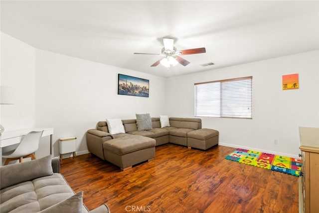 living room featuring a ceiling fan, visible vents, baseboards, and wood finished floors