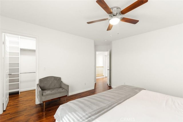 bedroom with wood finished floors, a ceiling fan, baseboards, a closet, and a walk in closet