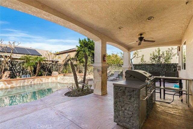 view of patio / terrace featuring an outdoor kitchen, a fenced backyard, a ceiling fan, and an outdoor pool