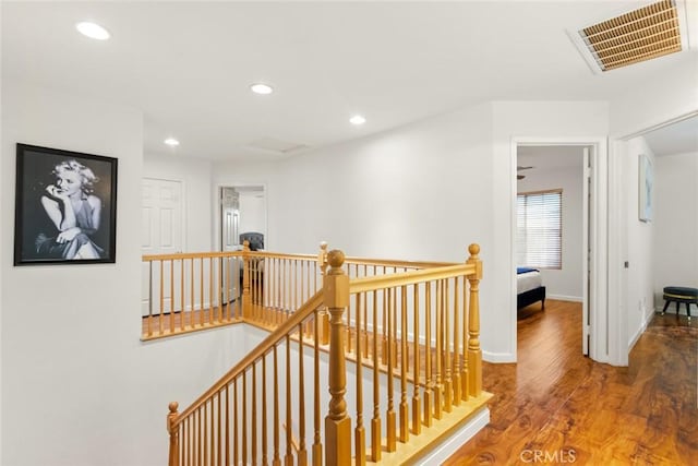 hallway featuring baseboards, visible vents, wood finished floors, an upstairs landing, and recessed lighting