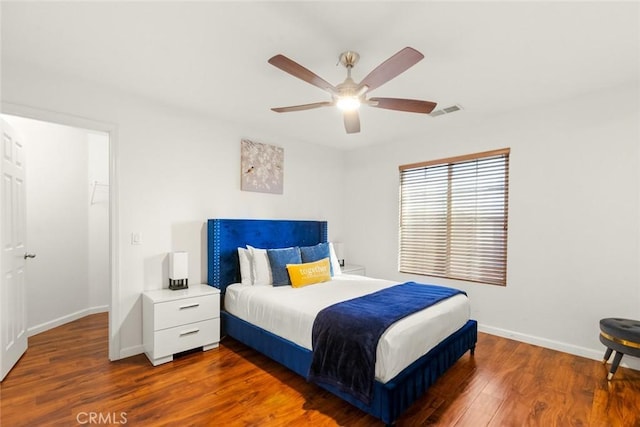 bedroom with a ceiling fan, wood finished floors, visible vents, and baseboards