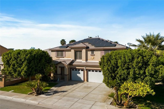 view of front of house featuring solar panels, stucco siding, concrete driveway, an attached garage, and a tiled roof