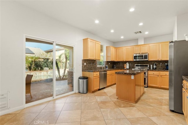 kitchen with visible vents, a kitchen island, stainless steel appliances, light brown cabinetry, and backsplash