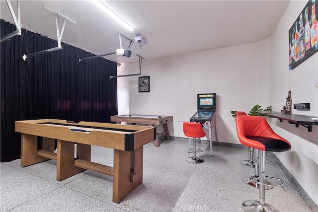 recreation room with a garage, baseboards, and speckled floor