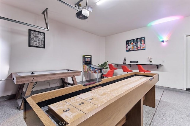 playroom with light speckled floor, a garage, and baseboards