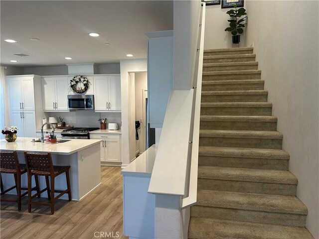 stairs with visible vents, wood finished floors, and recessed lighting