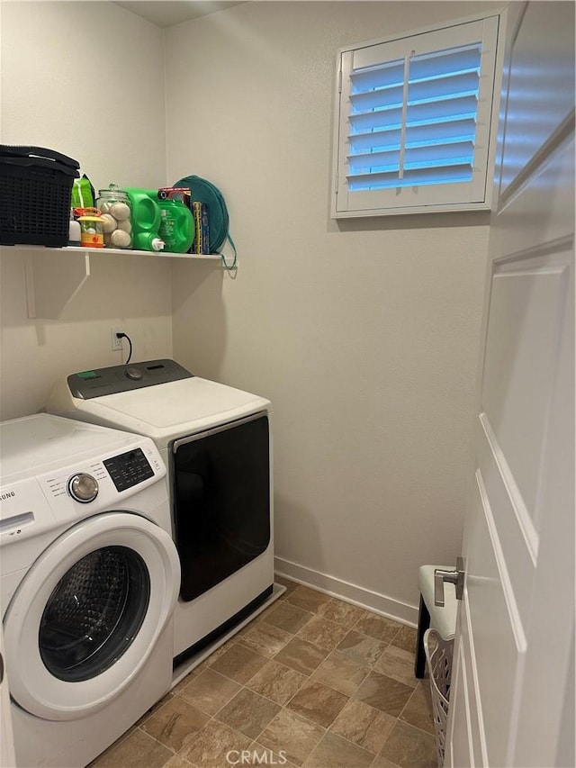 laundry area with laundry area, washing machine and dryer, baseboards, and stone finish flooring