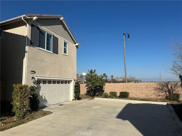 13906 Gazania Ln, Fontana, CA 92336 - view of home's exterior with a garage, concrete driveway, and stucco siding