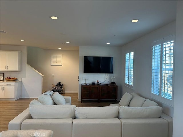 living area with baseboards, wood finished floors, and recessed lighting