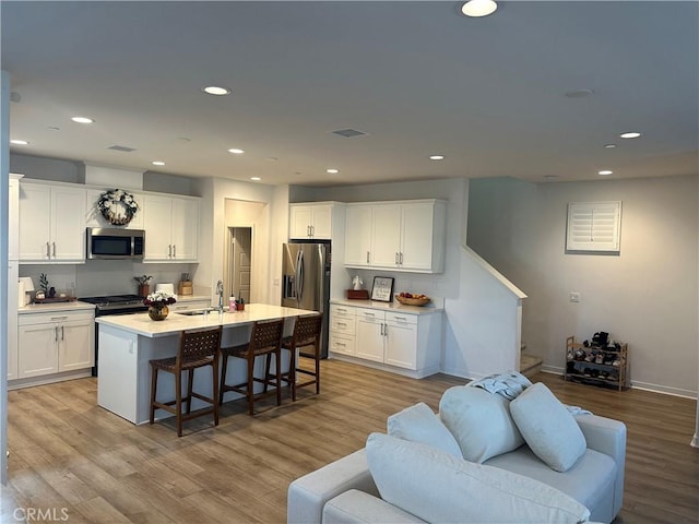 kitchen featuring white cabinets, appliances with stainless steel finishes, light countertops, and a sink