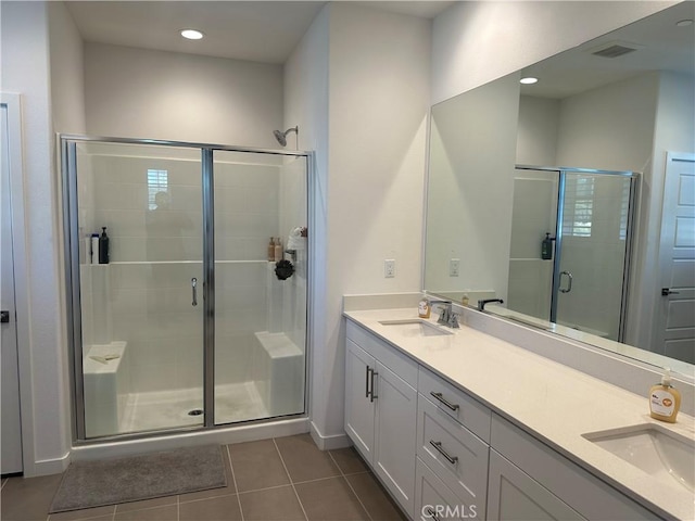 bathroom featuring a stall shower, visible vents, a sink, and tile patterned floors