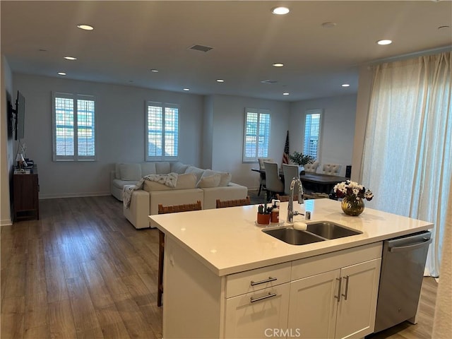 kitchen with a center island with sink, open floor plan, light countertops, white cabinetry, and a sink