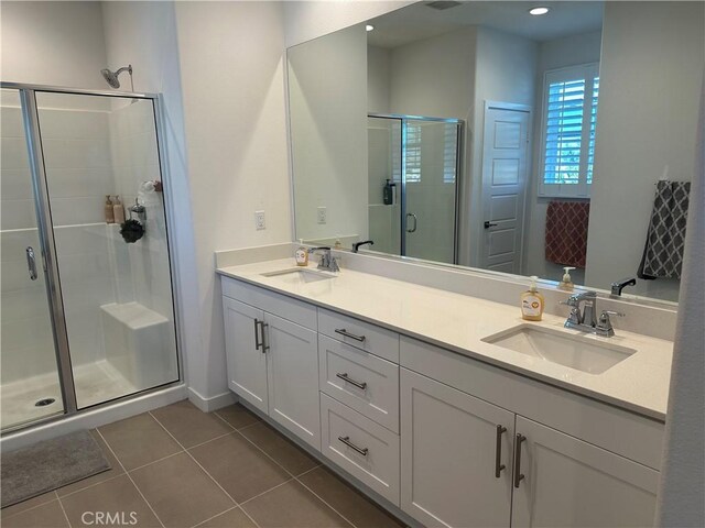 full bath with double vanity, a shower stall, a sink, and tile patterned floors