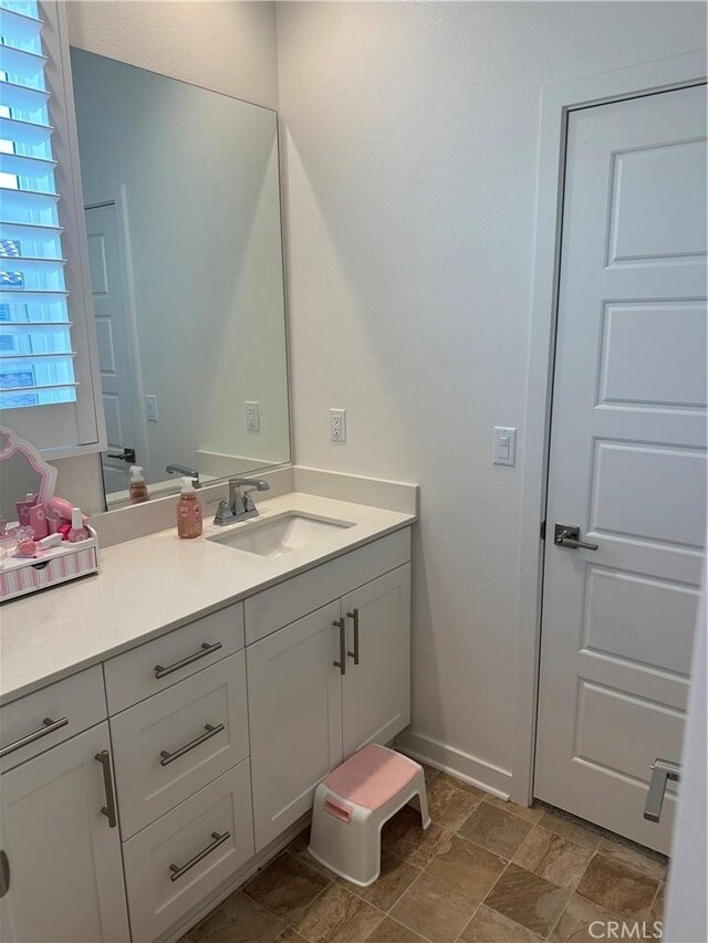 bathroom with stone finish floor and vanity