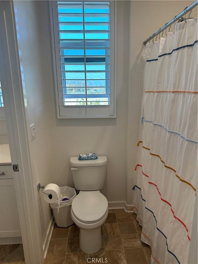 bathroom with curtained shower, baseboards, vanity, and toilet