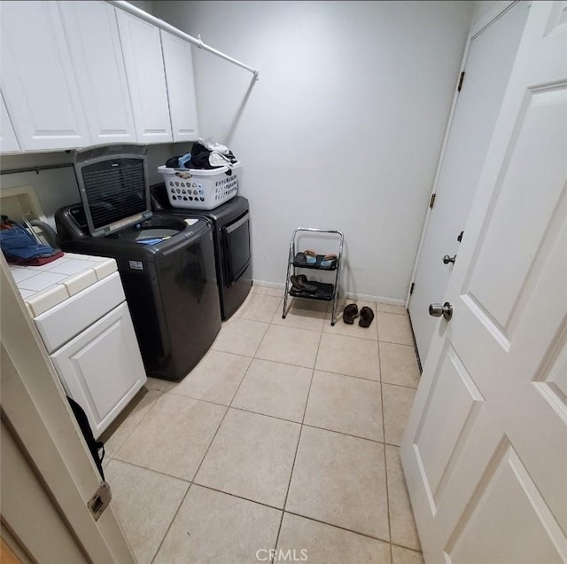 laundry room featuring cabinet space, baseboards, separate washer and dryer, and light tile patterned flooring