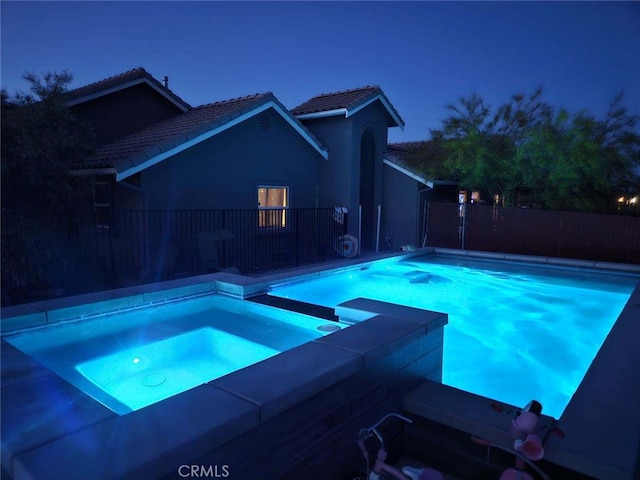 view of swimming pool featuring fence and an in ground hot tub