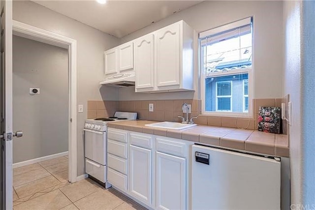 kitchen with tile countertops, under cabinet range hood, a sink, white cabinetry, and white electric range oven