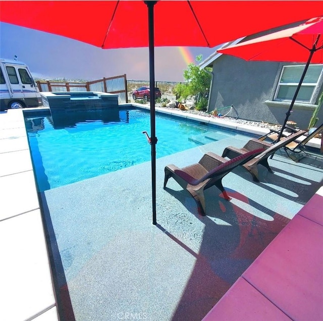 pool at dusk with fence and a pool with connected hot tub