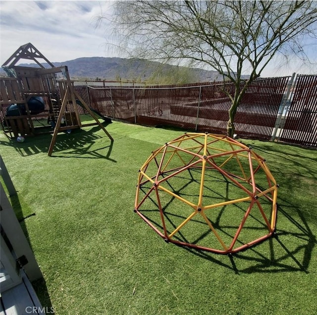 exterior space featuring a playground, fence, and a mountain view