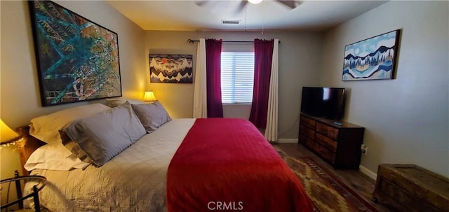 bedroom with ceiling fan, wood finished floors, visible vents, and baseboards