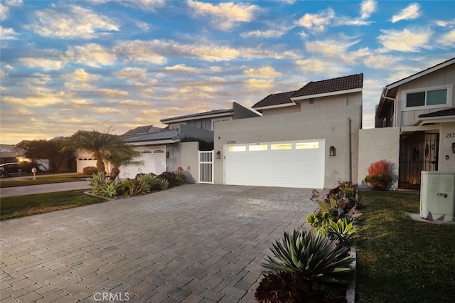 view of front facade with a garage, decorative driveway, a tiled roof, and stucco siding