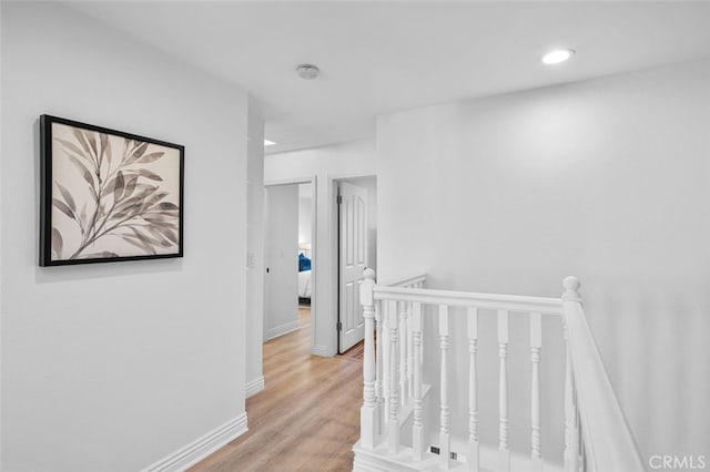 corridor featuring light wood-style floors, recessed lighting, an upstairs landing, and baseboards