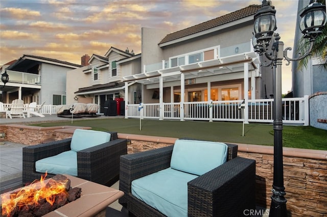 rear view of property featuring a fire pit, a pergola, and stucco siding