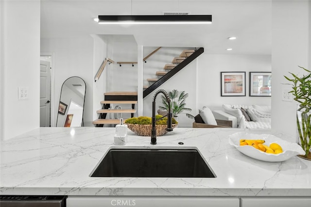 kitchen with stainless steel dishwasher, visible vents, light stone counters, and a sink