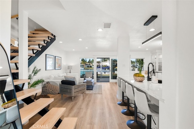 living room featuring light wood-type flooring, plenty of natural light, visible vents, and recessed lighting