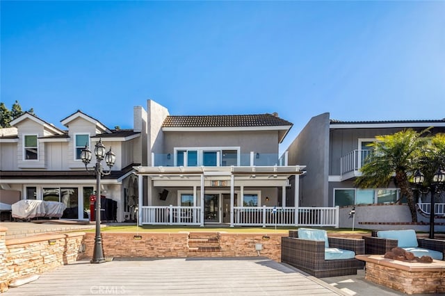 back of property with a wooden deck, fence, and stucco siding