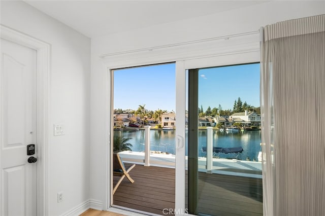 entryway featuring a water view, baseboards, and wood finished floors