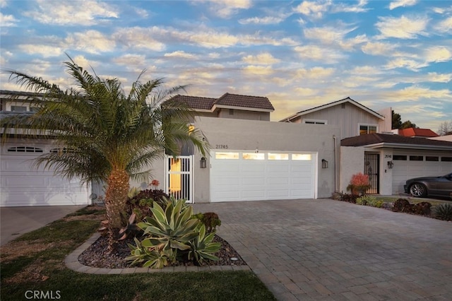 view of front of home featuring an attached garage, decorative driveway, and stucco siding