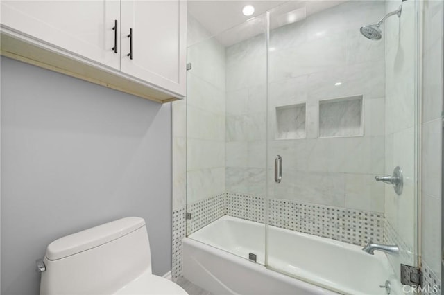 bathroom featuring bath / shower combo with glass door and toilet