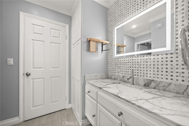 bathroom with baseboards, ornamental molding, wood finished floors, and vanity