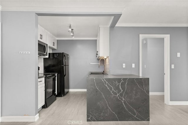 kitchen with dark stone counters, white cabinets, crown molding, black appliances, and a sink