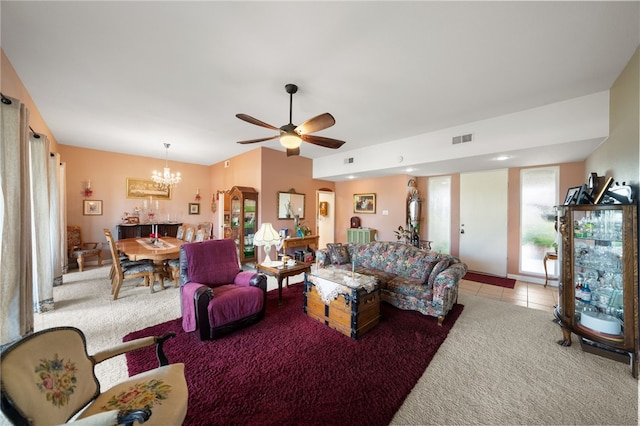 living room featuring ceiling fan with notable chandelier, light tile patterned floors, visible vents, and light colored carpet