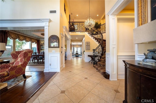 entryway with stairway, visible vents, a chandelier, and crown molding